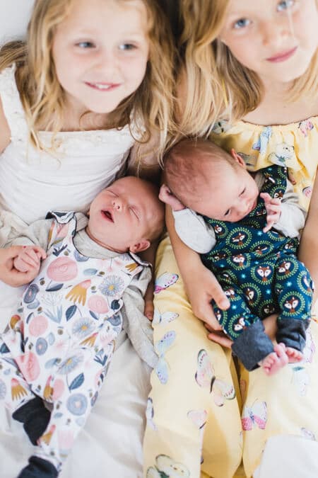 Blick von oben auf Schwester die ihre neugeborenen Geschwister auf dem Schoß halten