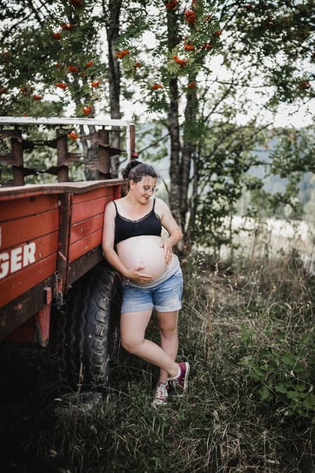Schwangere Frau lehnt an einem Anhänger