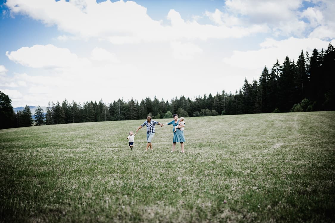 Familie rennt Hand in Hand über eine Wiese