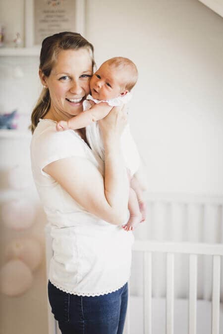 Mutter mit ihrem Baby auf dem Arm  stehen im Kinderzimmer