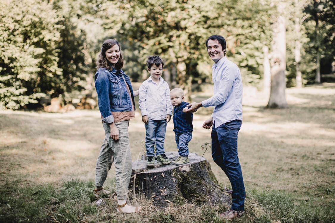 Familie steht in der Natur auf einem Baumstumpf