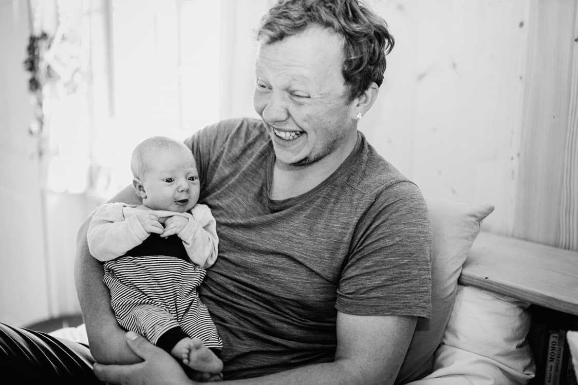 Papa lachend mit Baby auf dem Schoß