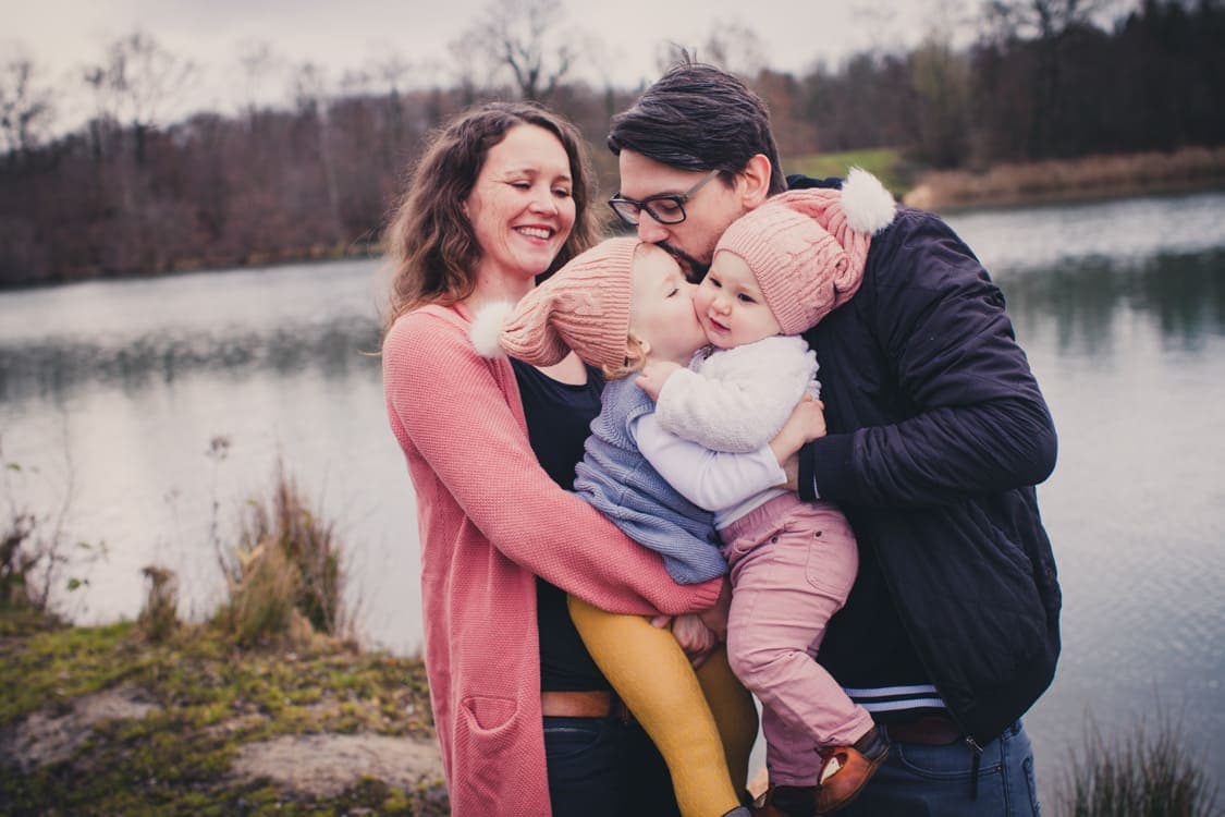 Familie mit zwei Kindern kuscheln zusammen am See