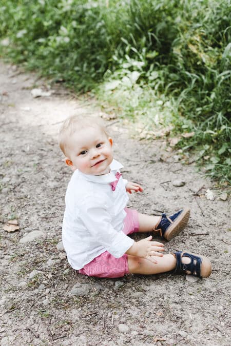 Kleiner Junge mit Fliege um den Hals sitzt auf dem Boden