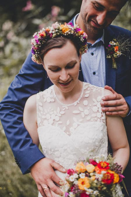 Bräutigam steht hinter Braut und legt den Arm um sie