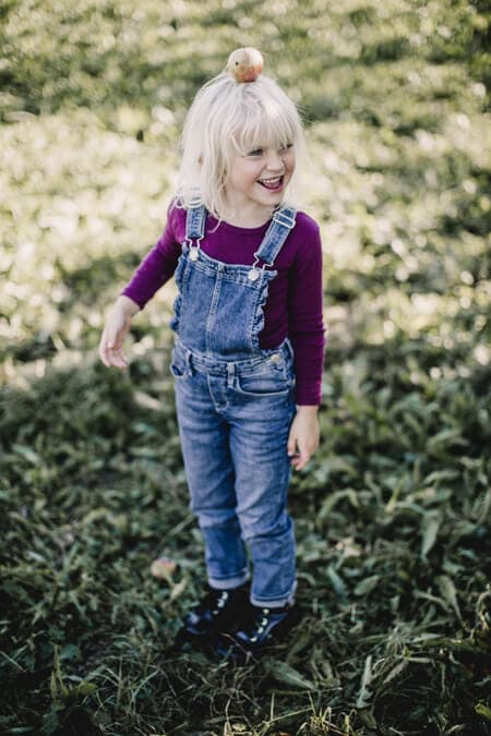 Mädchen auf einer Wiese mit Apfel auf dem Kopf