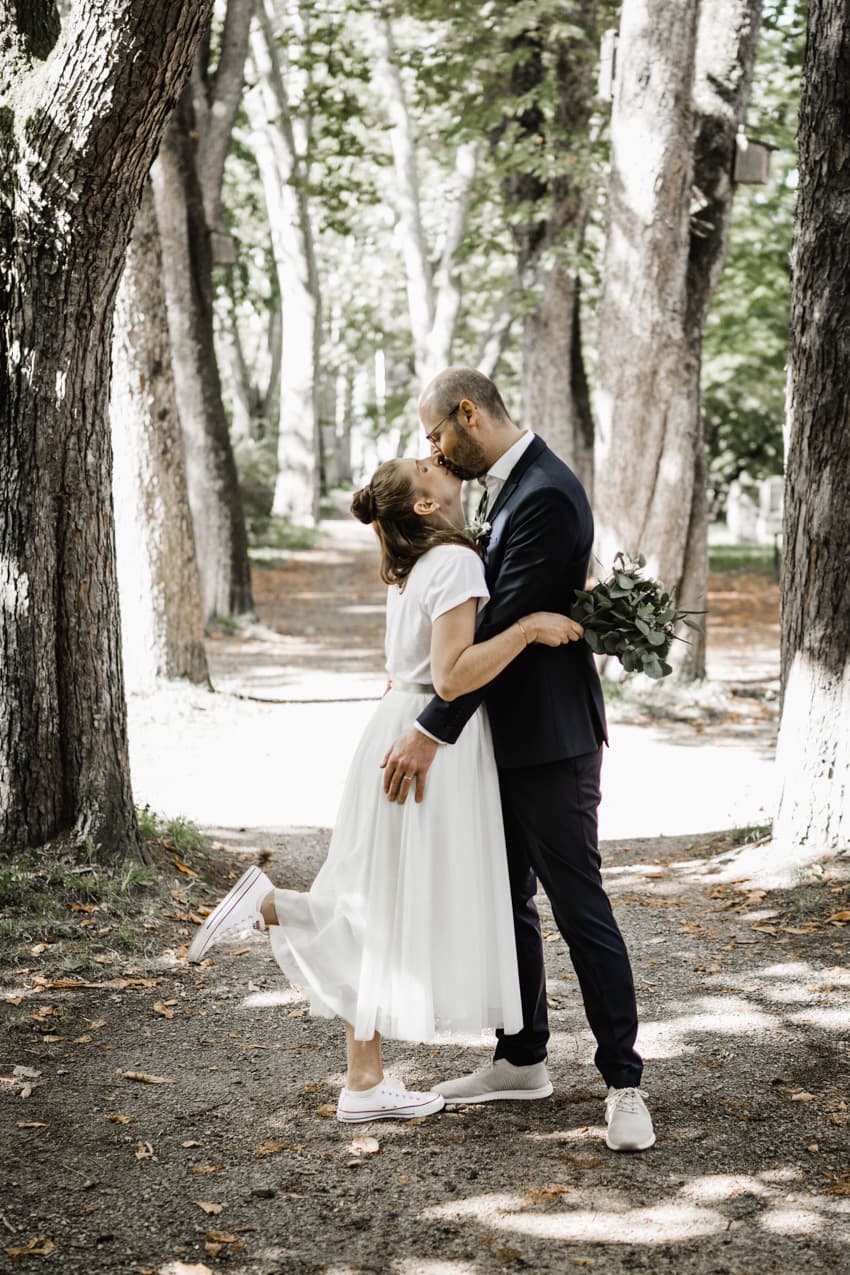 Brautpaar küsst sich in einer Allee