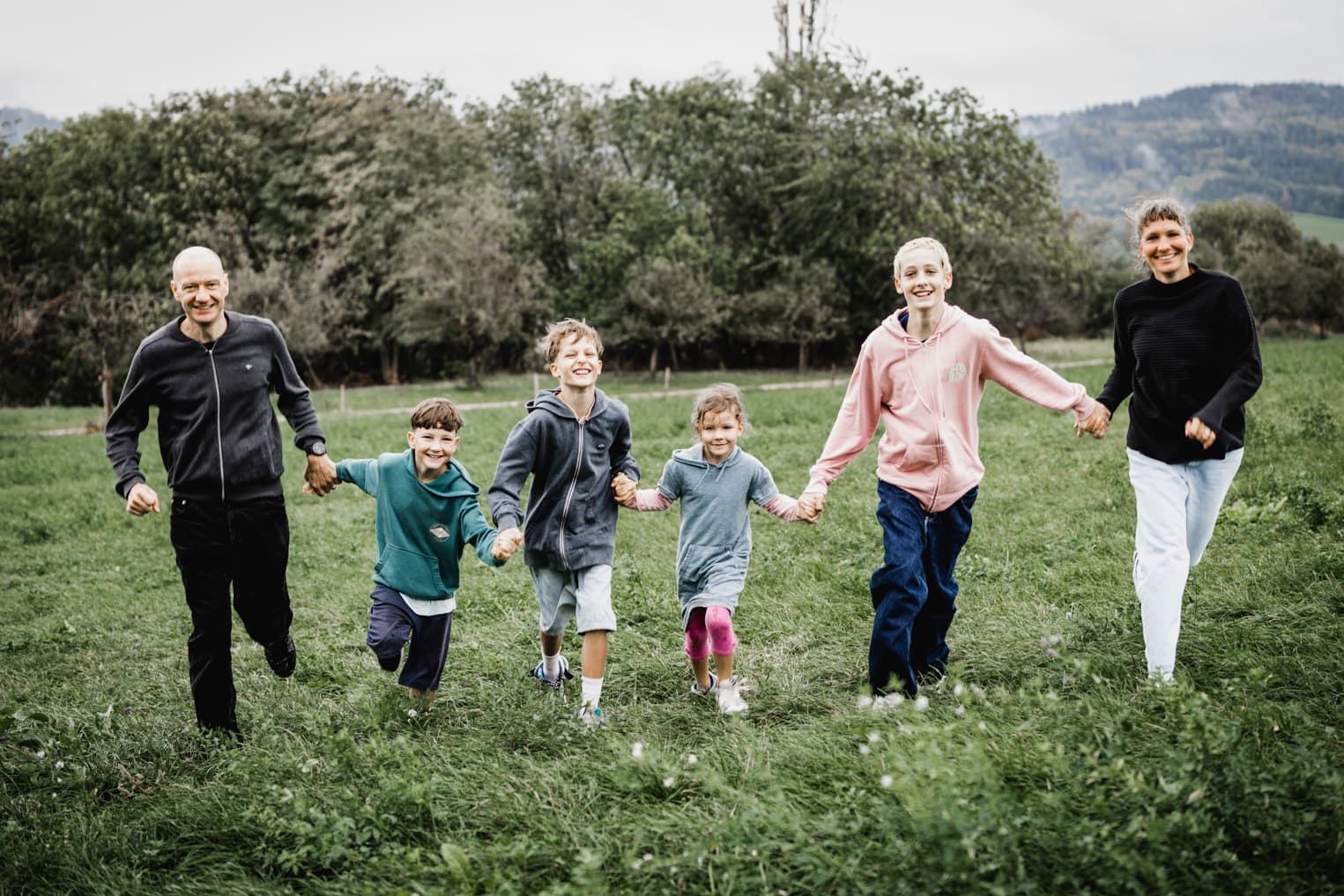 Familie rennt Hand in Hand über eine Wiese