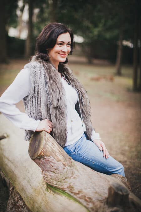 Frau lehnt an einem Baumstamm und schaut dabei nicht in die Kamera