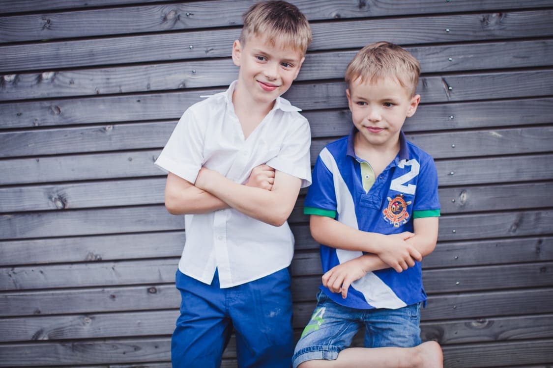 Brüder lehnen an einer Bretterwand