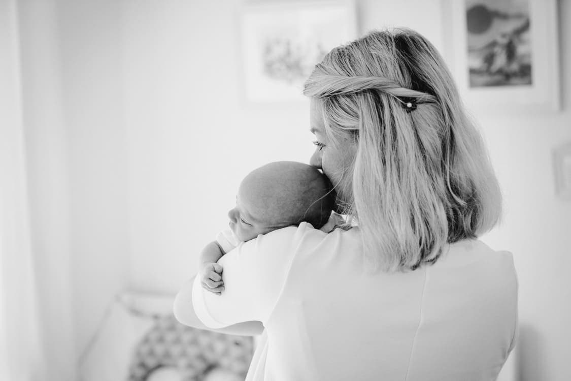 Mutter von hinten mit Baby über der Schulter