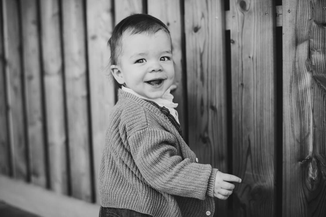 Kleiner Junge vor Holzbretter Wand in SW fotografiert