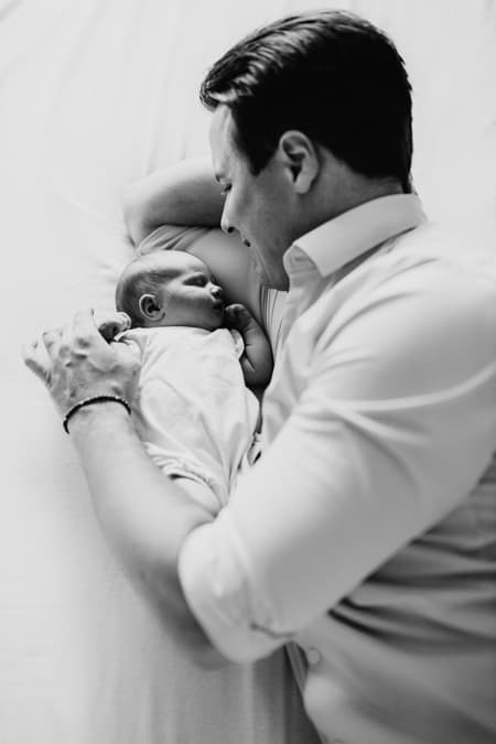 Papa liegt mit Baby auf dem Bett