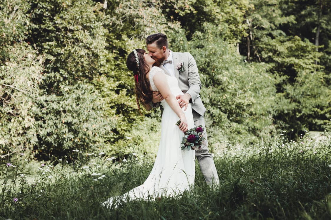 Brautpaar küsst sich auf einer Wiese
