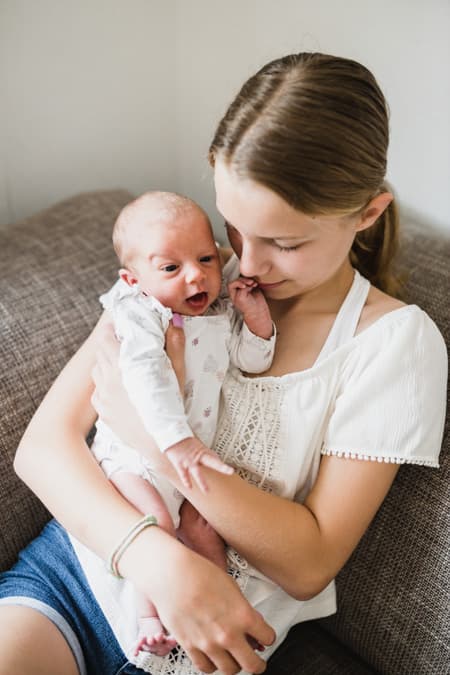 Große Schwester mit Baby auf dem Arm