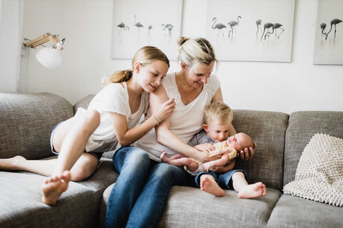 Mutter mit ihren drei Kindern auf dem Sofa
