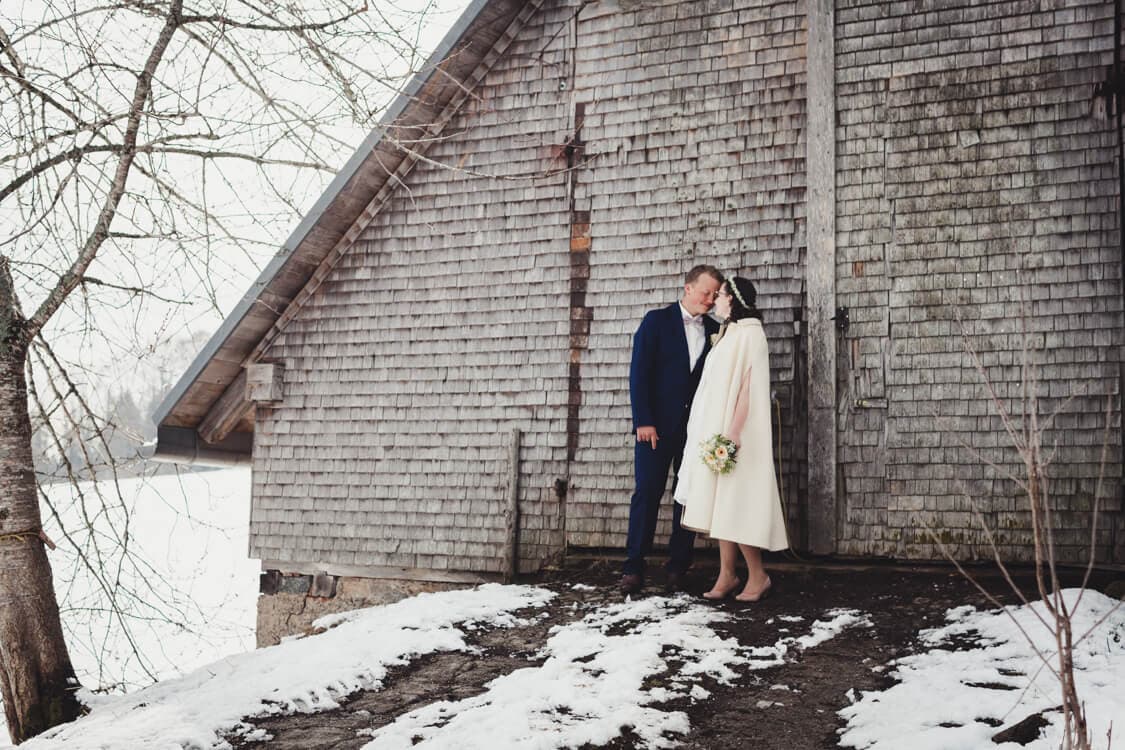 Brautpaar vor scheune im Schnee