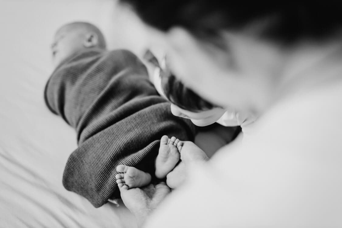 Mutter hält die Füße von ihrem Baby in ihren Händen