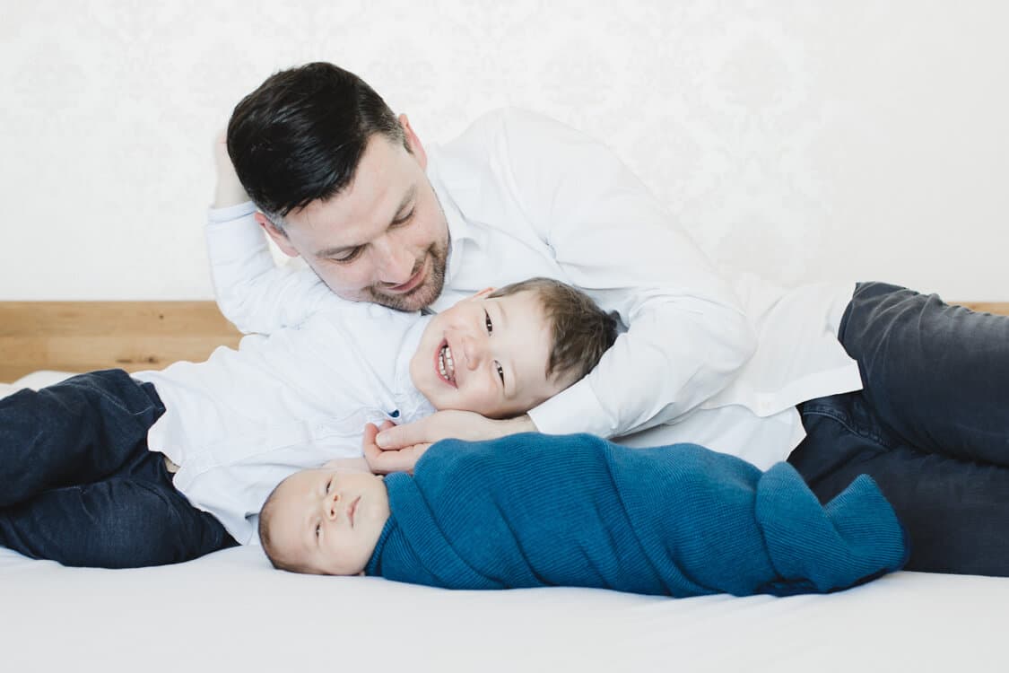 Vater mit seinen beiden Söhnen auf dem Bett