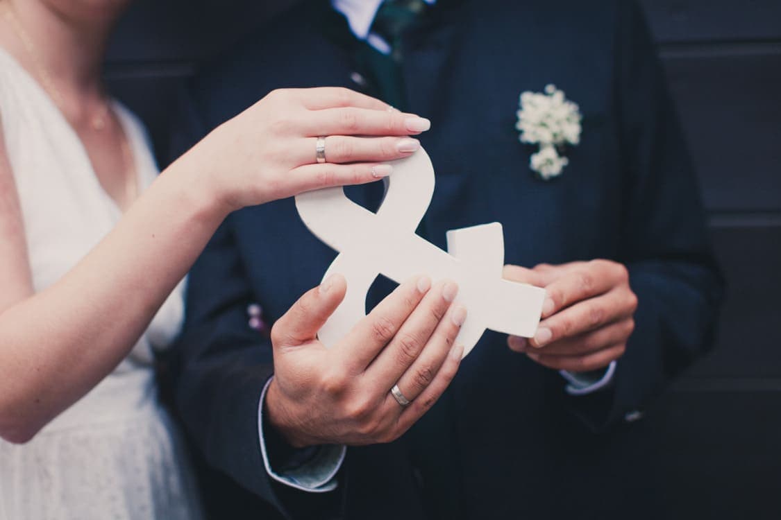 Brautpaar hält ein & Zeichen zusammen in den Händen