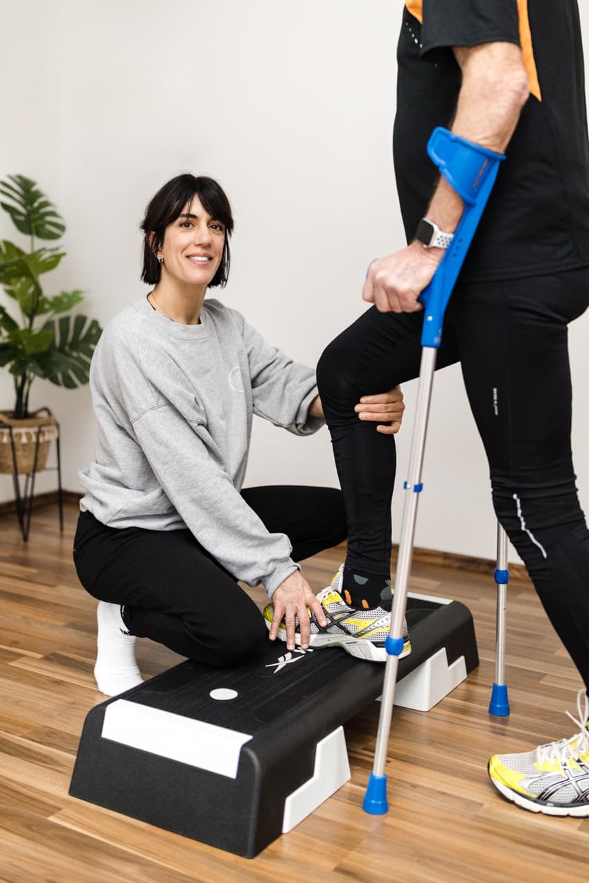 Physiotherapeutin behandelt Mann mit Krücken