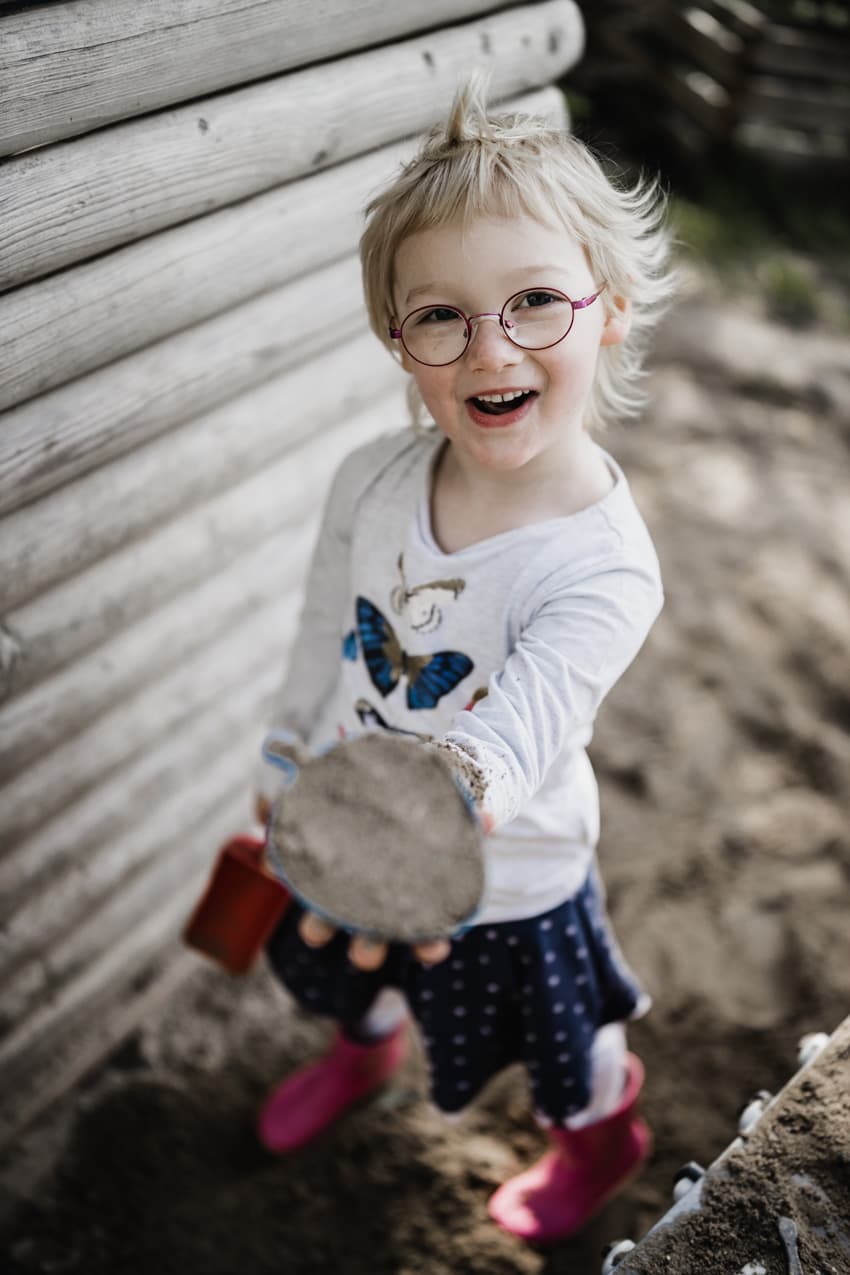 Mädchen mit Sandkuchen im Sandkasten