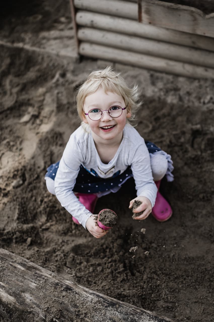 Mädchen sitzt im Sandkasten