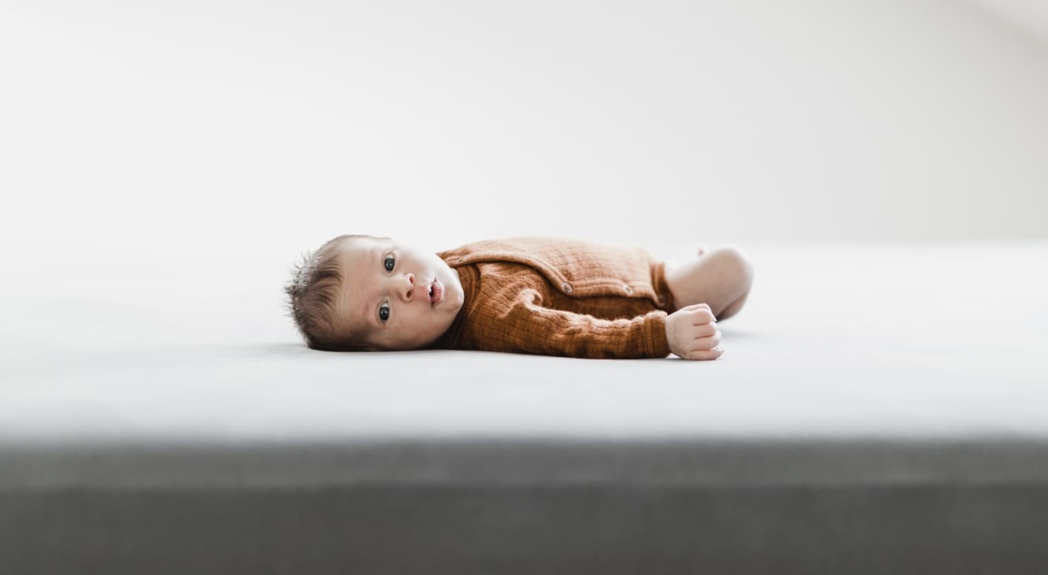 Baby liegt auf einem Bett