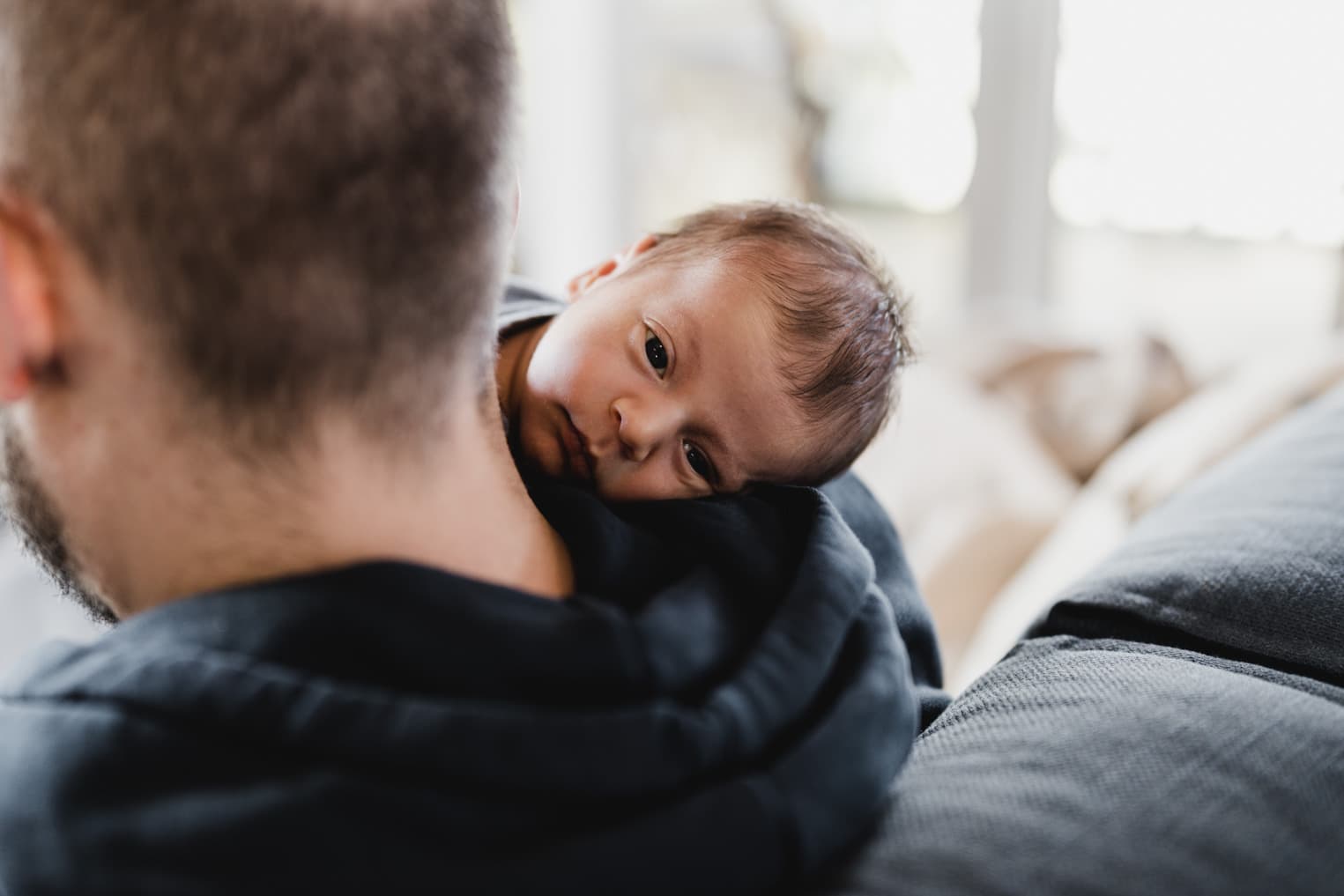 Baby blickt über die Schulter des Vaters