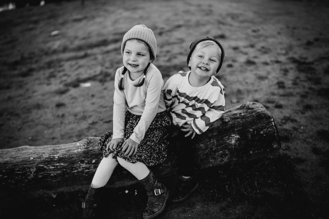 Junge und Maedchen auf Baumstamm