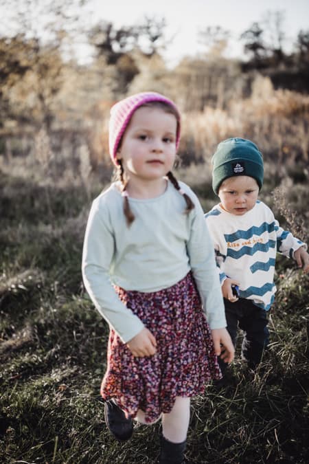 Maedchen und Junge laufen ueber eine Wiese