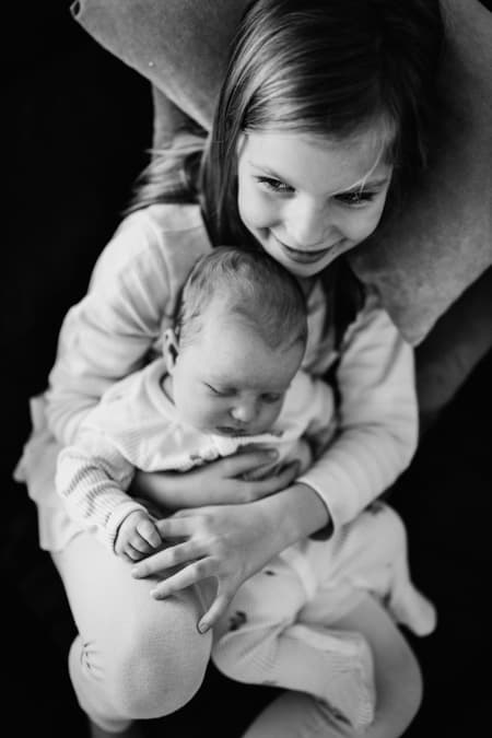 Baby auf dem Schoß der Schwester