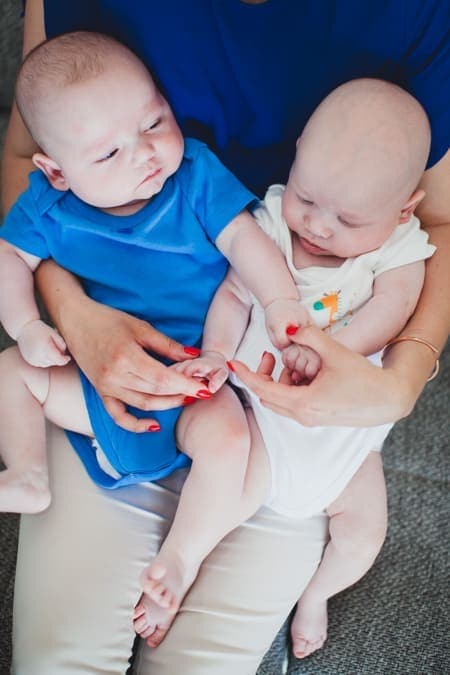 Zwillingsbabys sitzen auf dem Schoß von Mama