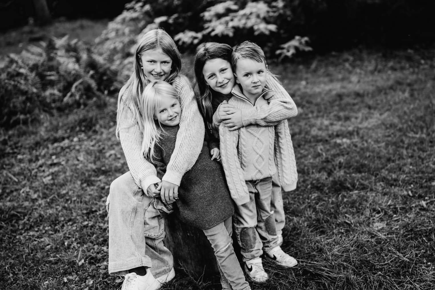 Vier Geschwister sitzen auf einer Wiese