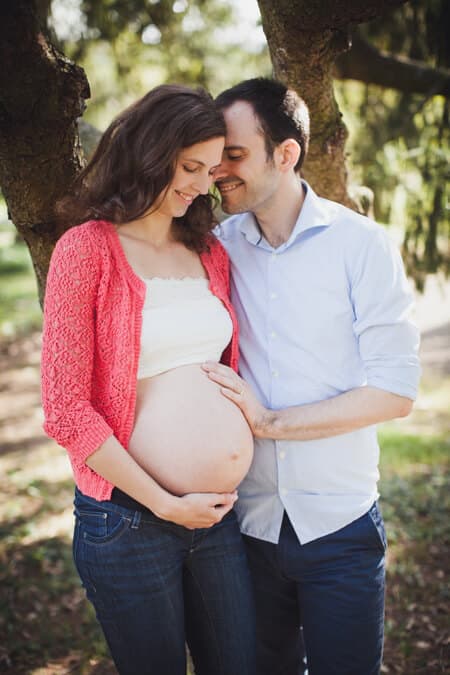 Glückliche werdende Eltern unter einem Baumast