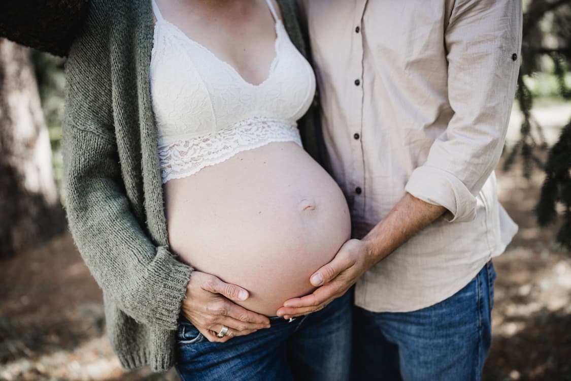 Mann und Frau mit Händen auf dem Babybauch