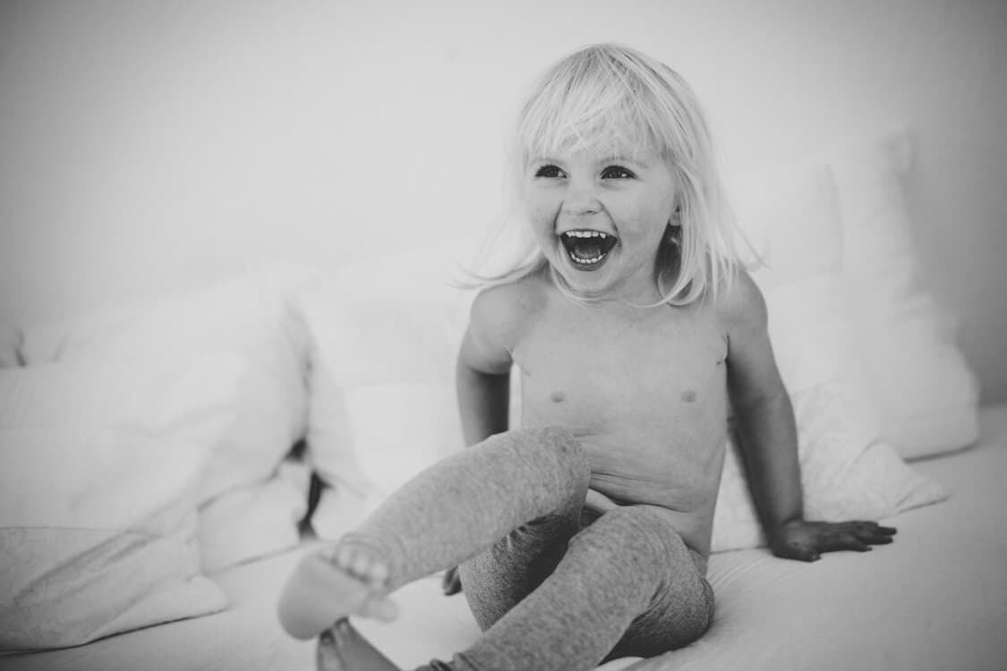 lachendes Mädchen tobt auf Bett