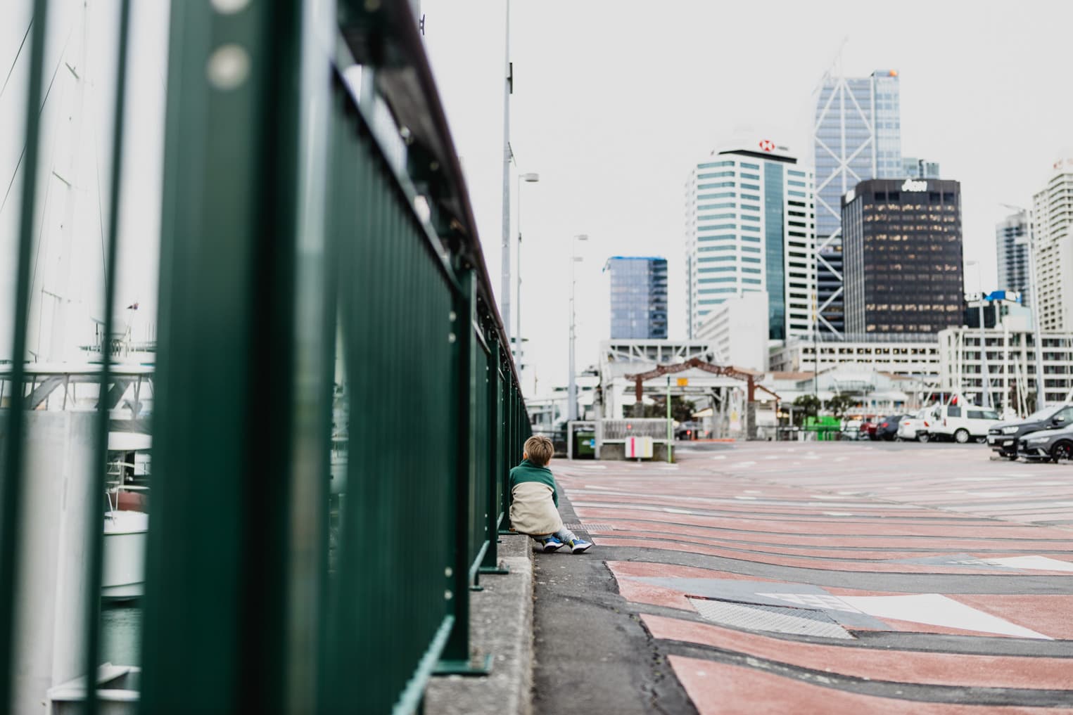 Junge sitzt am Hafen in Auckland