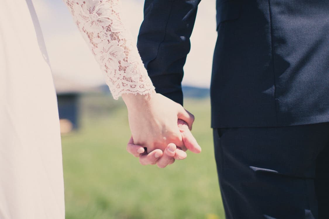 Nahaufnahme vom Brautpaar welches sich an den Händen hält