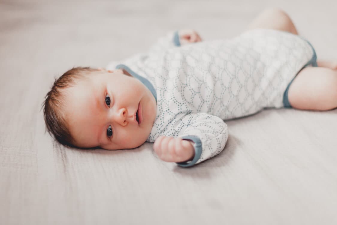 Babyjunge liegt auf einem Bett