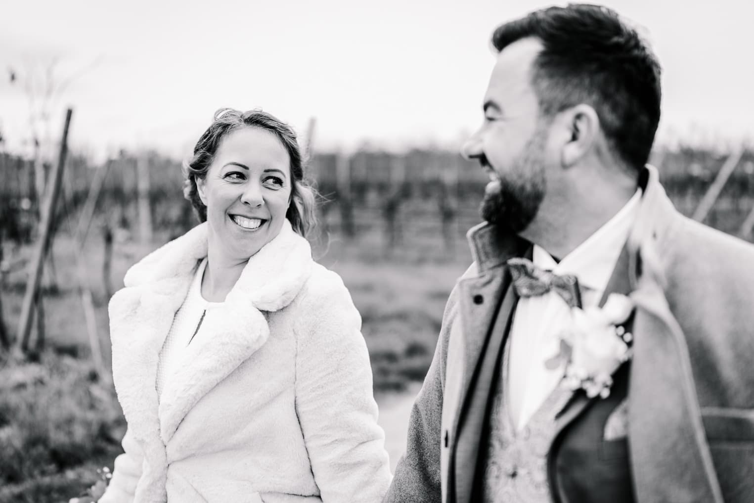 Brautpaar spaziert und Braut blickt zum Bräutigam, natürliche Hochzeitsfotografie