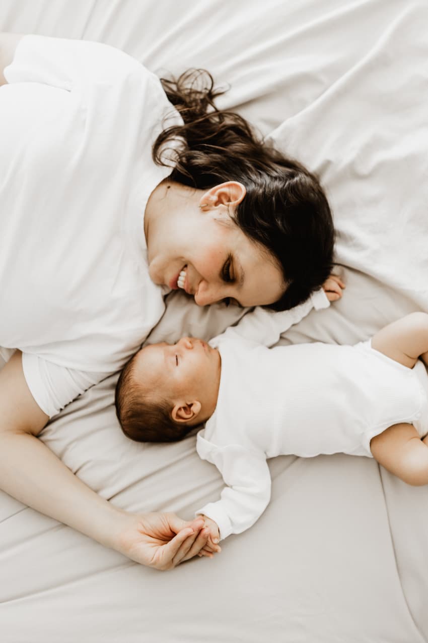 Mutter liegt Kopf an Kopf mit ihrem Baby, intime Aufnahme zu Hause