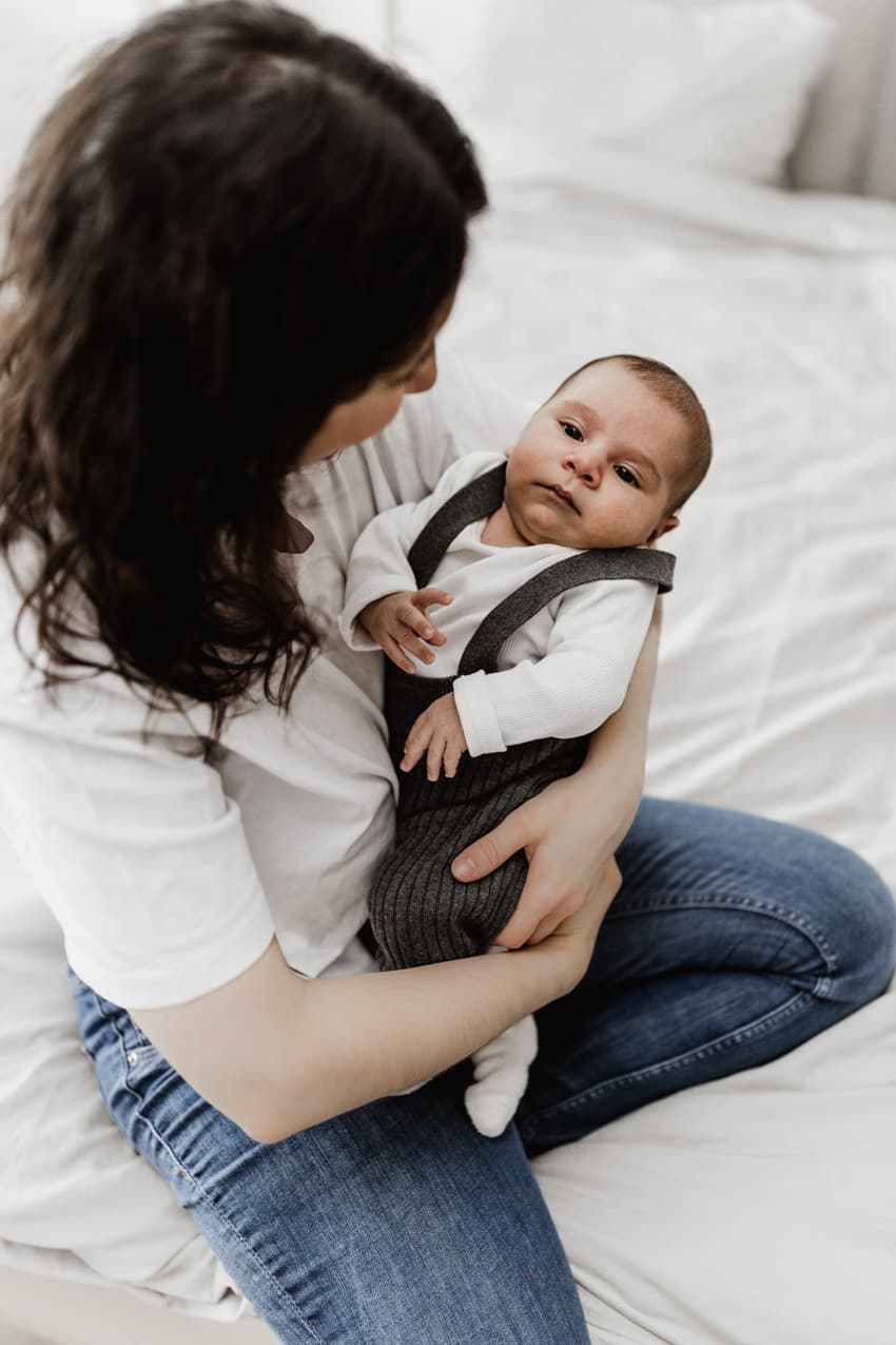 Baby liegt entspannt im Arm der Mutter während des Neugeborenen-Shootings