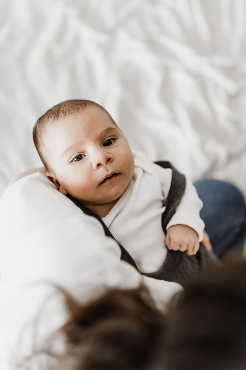 Baby liegt im Arm der Mutter während des Neugeborenen-Shootings