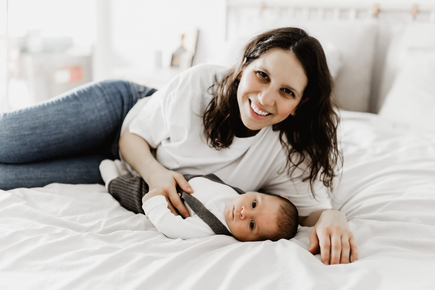 Mutter liegt gemeinsam mit ihrem Baby auf dem Bett beim Homeshooting