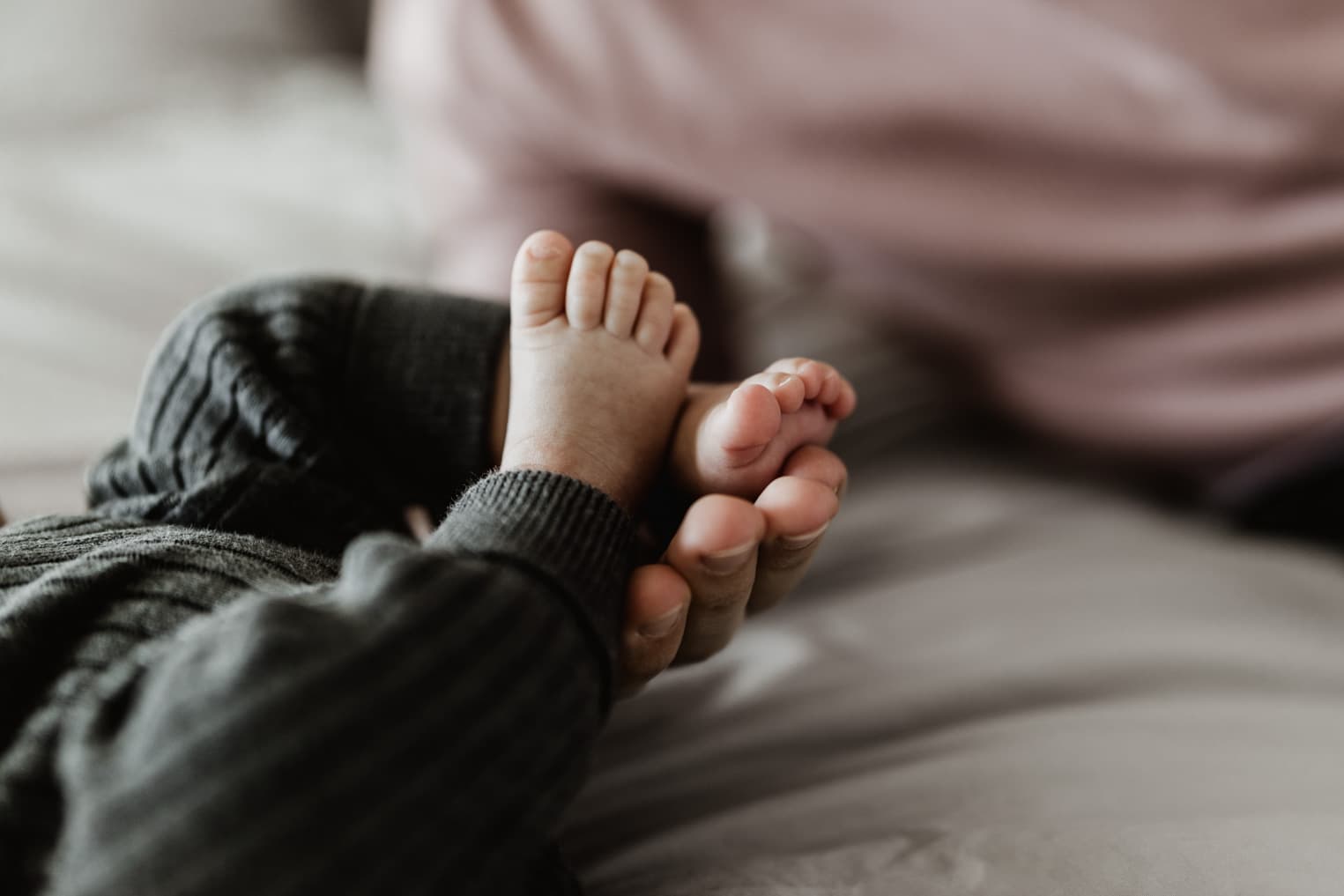Kleine Babyfüße liegen in der Hand des Vaters, Nahaufnahme beim Homeshooting